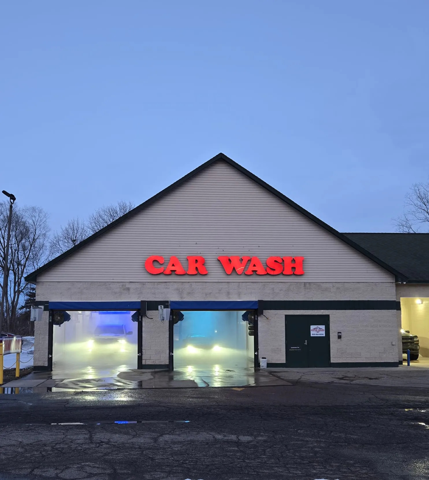 Al's Super Wash touchless car wash on Dort Hwy lit at dusk with snow on the ground and cars in the wash bays