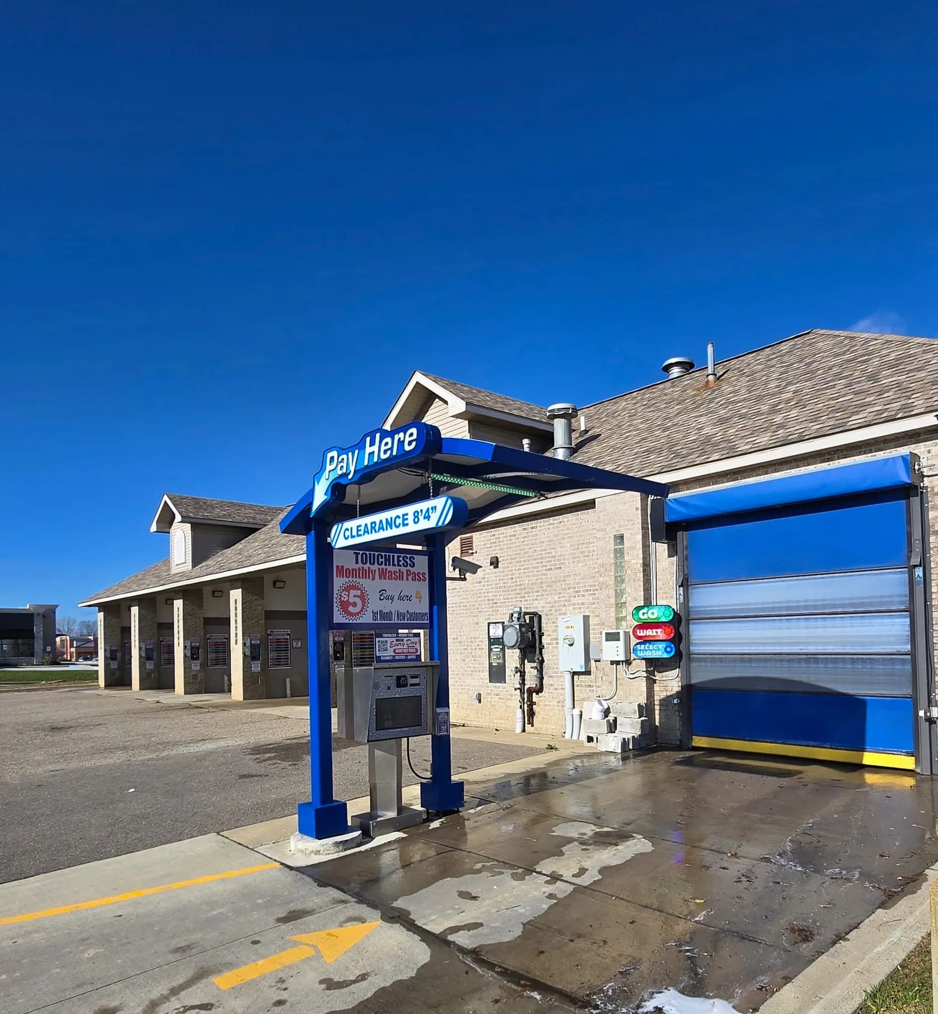 Pay station under the Pay Here canopy at the Al's Super Wash touchless car wash in Fenton, Michigan, with a $5 first month monthly wash pass sign