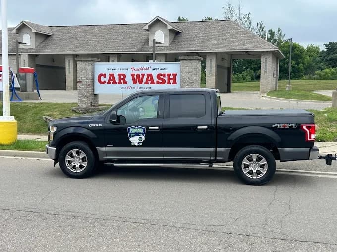 Clean black Ford F-150 with a glossy finish parked in front of the Al's Super Wash touchless car wash sign