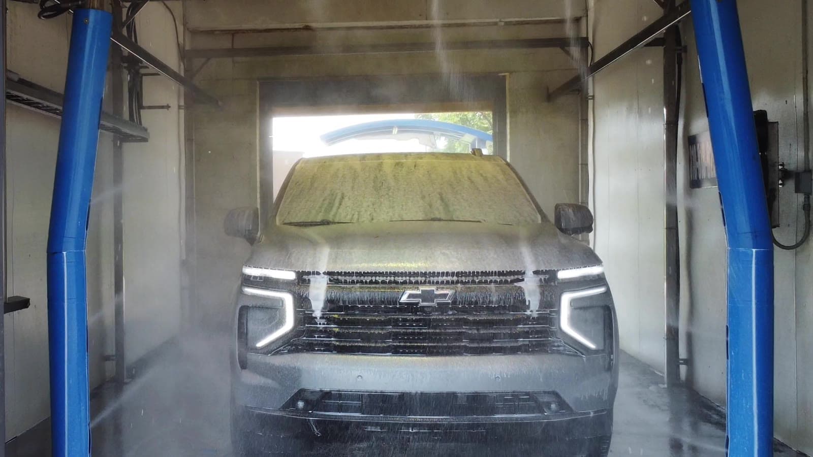 SUV coated in presoak detergent as high-pressure jets spray inside an Al's Super Wash touchless bay