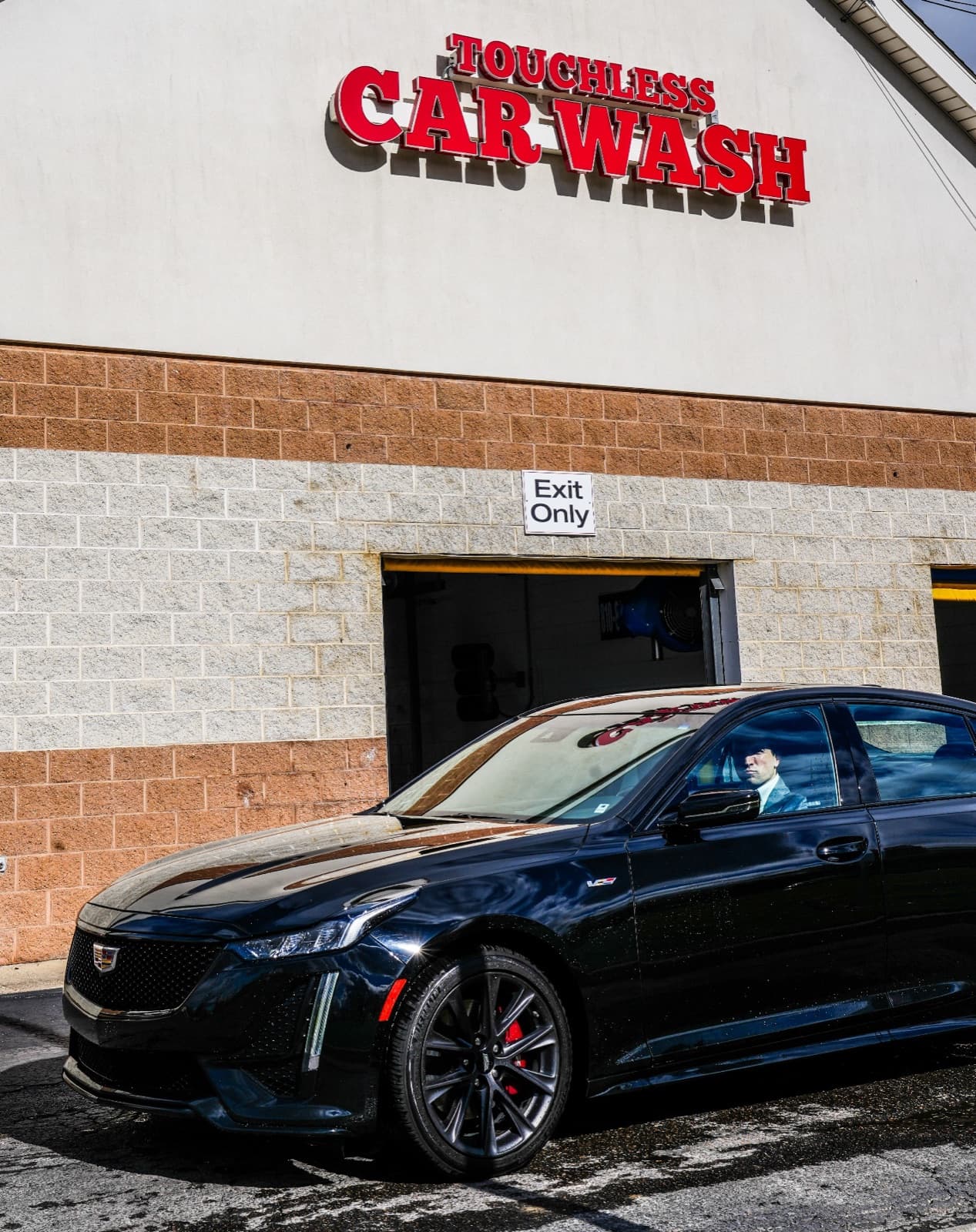 Black luxury sedan exiting Al's Super Wash touchless car wash building