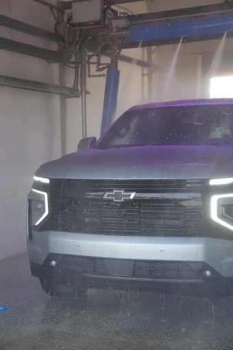 Chevrolet SUV being rinsed by high pressure jets inside an Al's Super Wash touchless bay